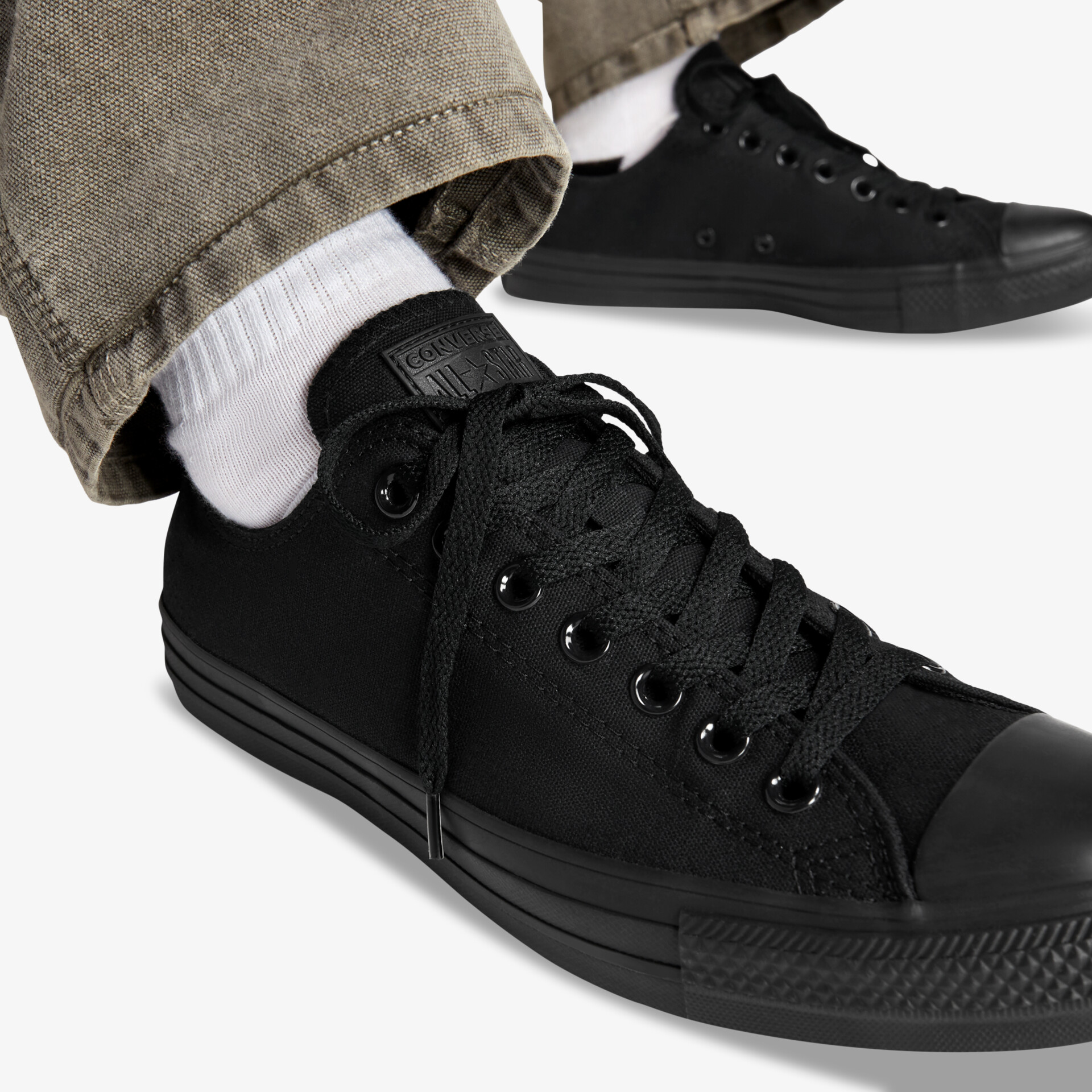 Schwarze Sneaker getragen mit sichtbarer Schnürung und robuster Gummisohle für flexiblen Tragekomfort