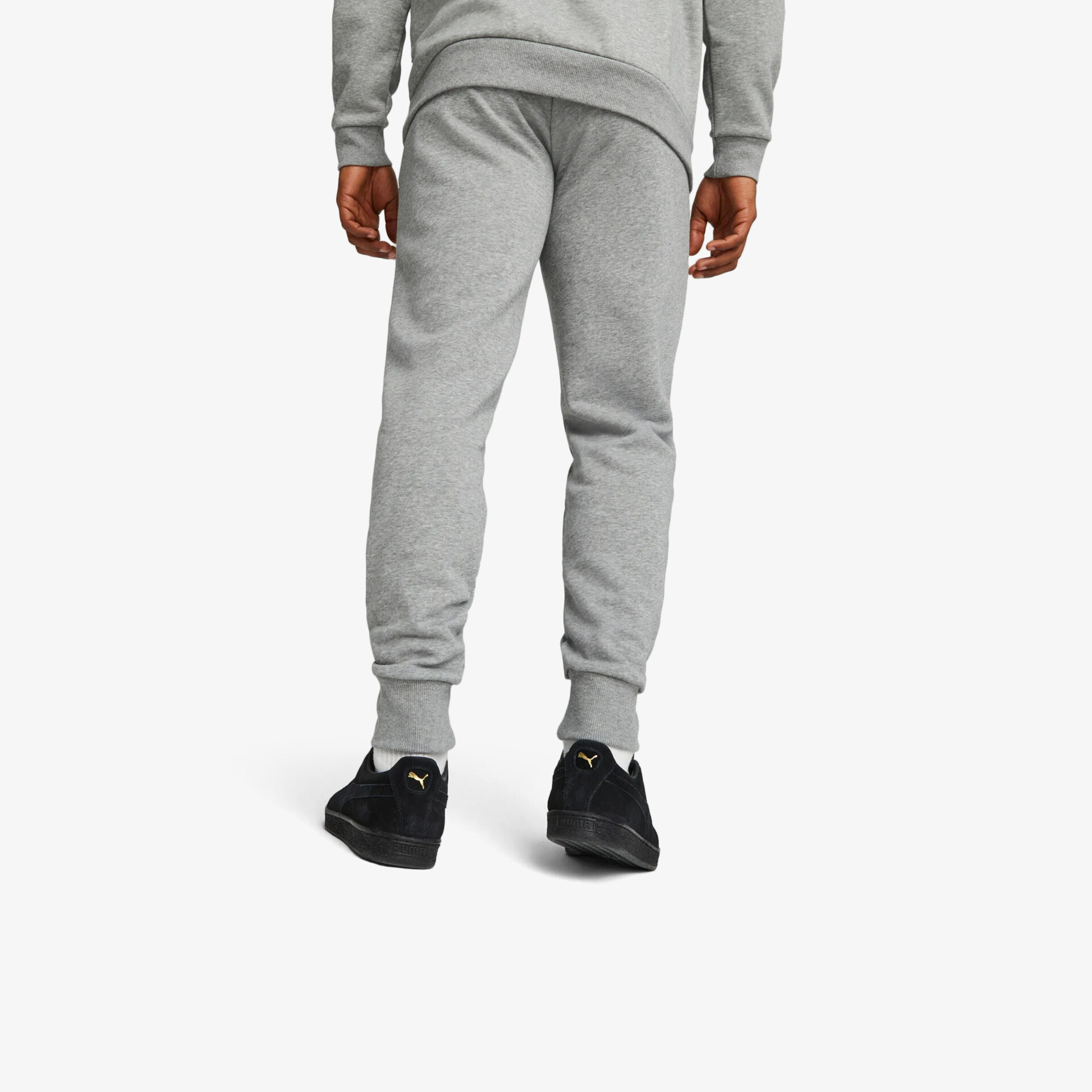 Schwarze Sneaker mit komfortabler Passform und rutschfester Sohle, getragen von hinten von einer Person mit grauer Hose