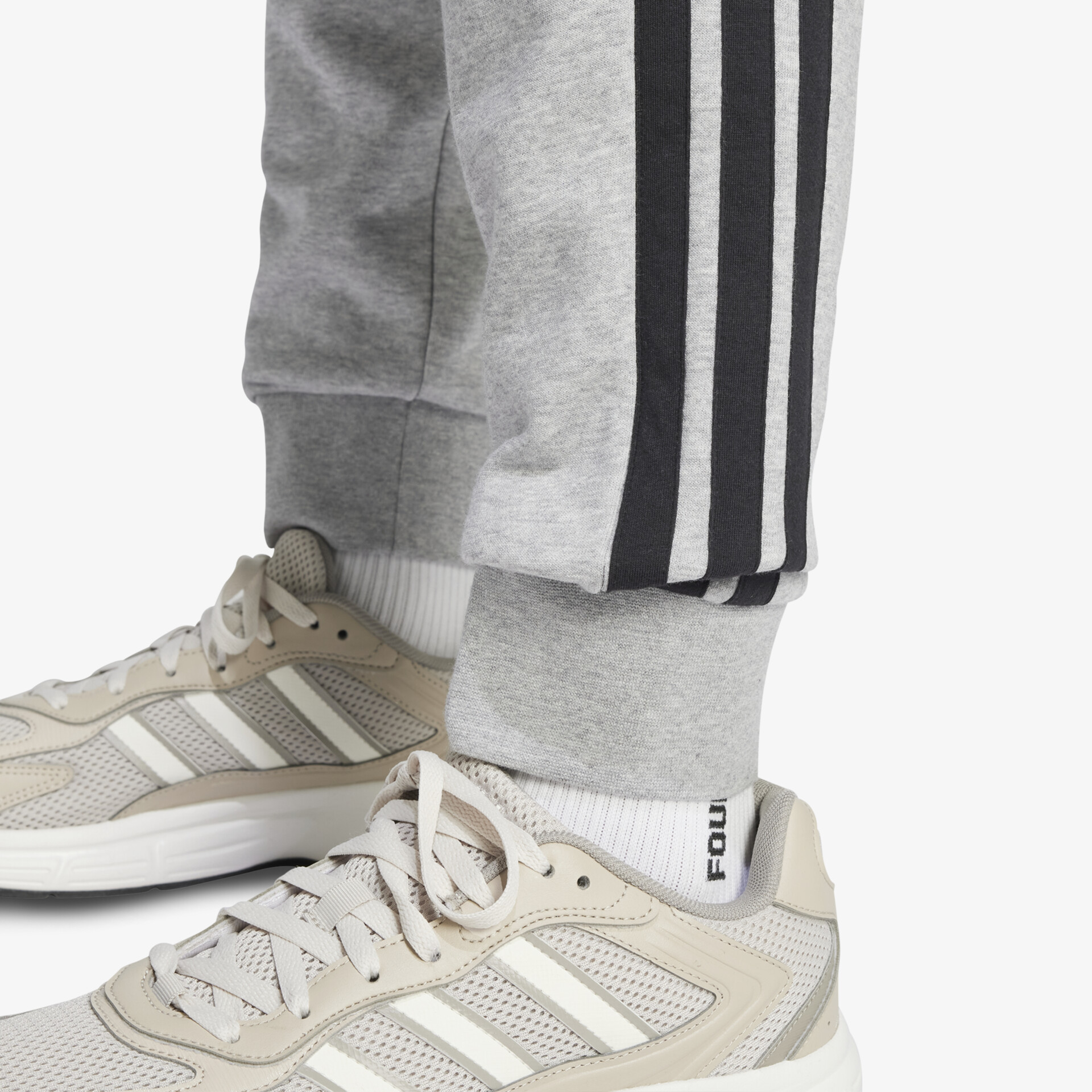 Beige Sneaker getragen mit grauer Jogginghose, atmungsaktiv und bequem für sportliche Aktivitäten