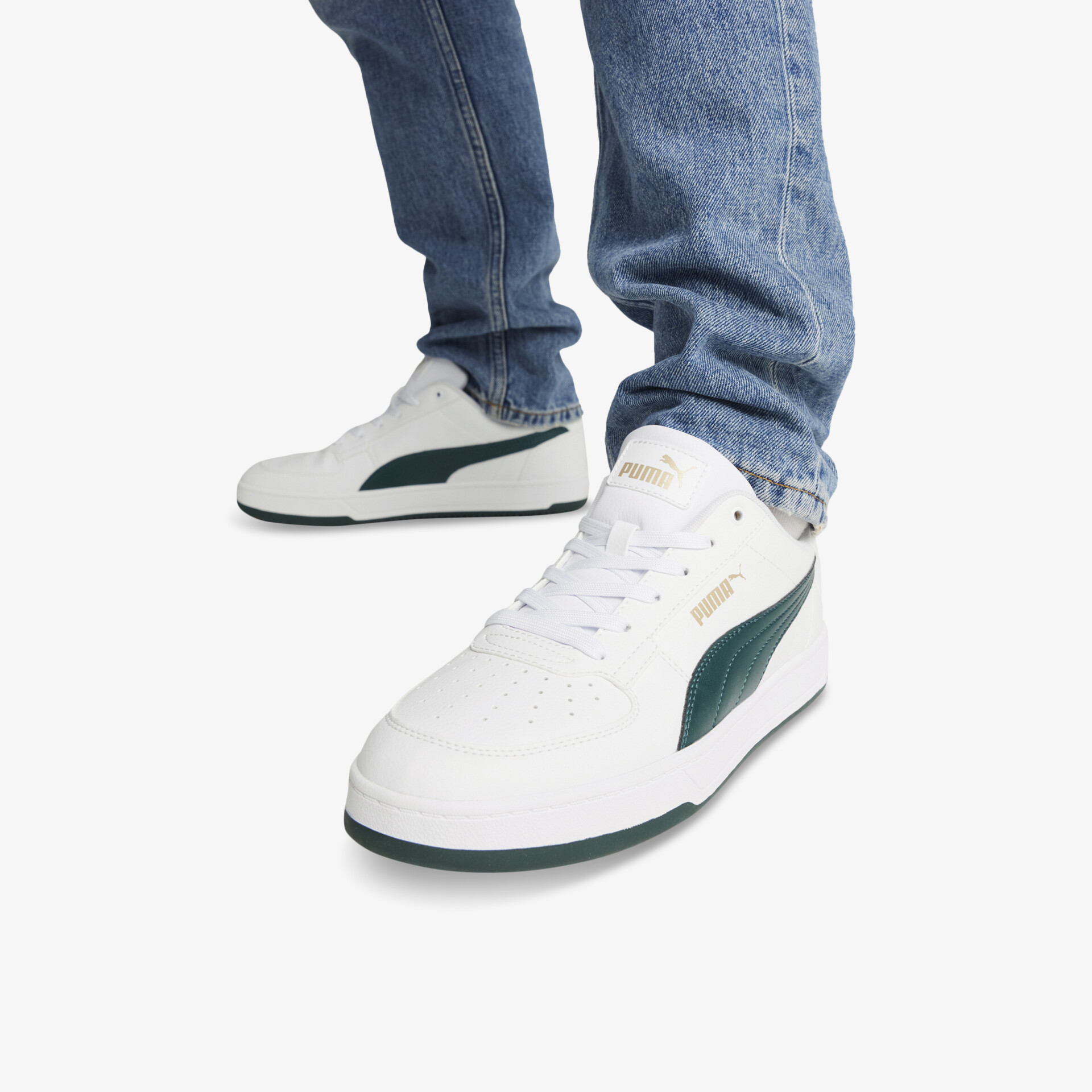 Weiße Sneaker mit grünem Markenstreifen in schräger Frontansicht, getragen und kombiniert mit blauen Jeans