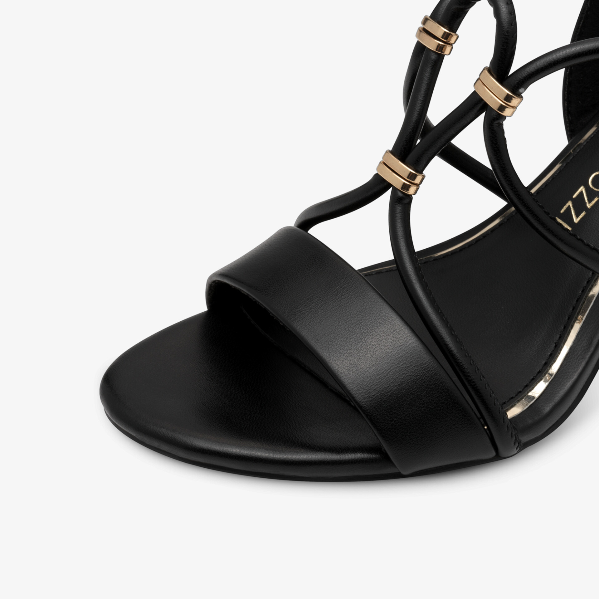 Detailaufnahme einer schwarzen Sandalette mit eleganten Riemen und goldenen Schmuckelementen in hochwertiger Verarbeitung