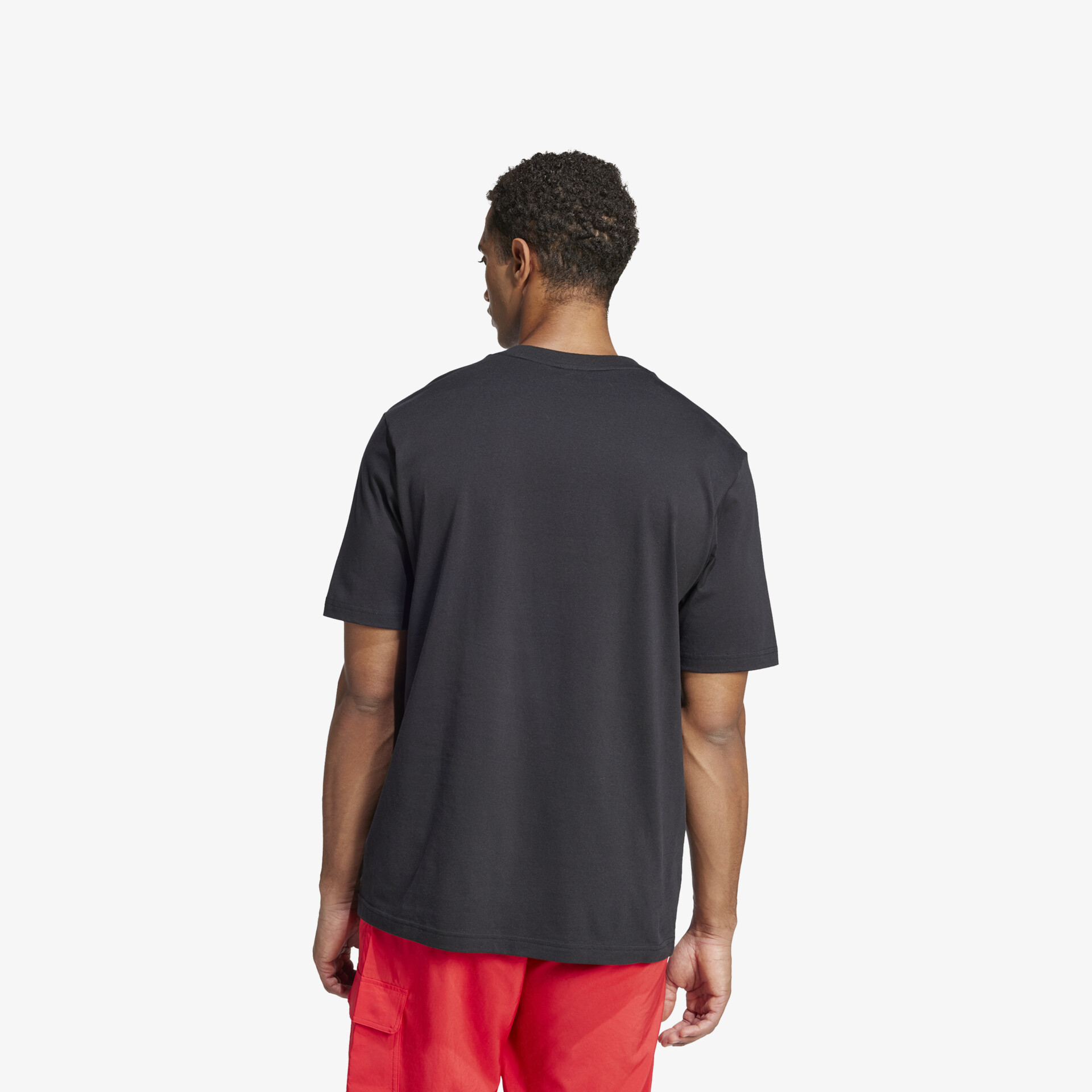 Person trägt schwarzes T-Shirt hinten mit roter Hose, entspannter und lässiger Alltagslook