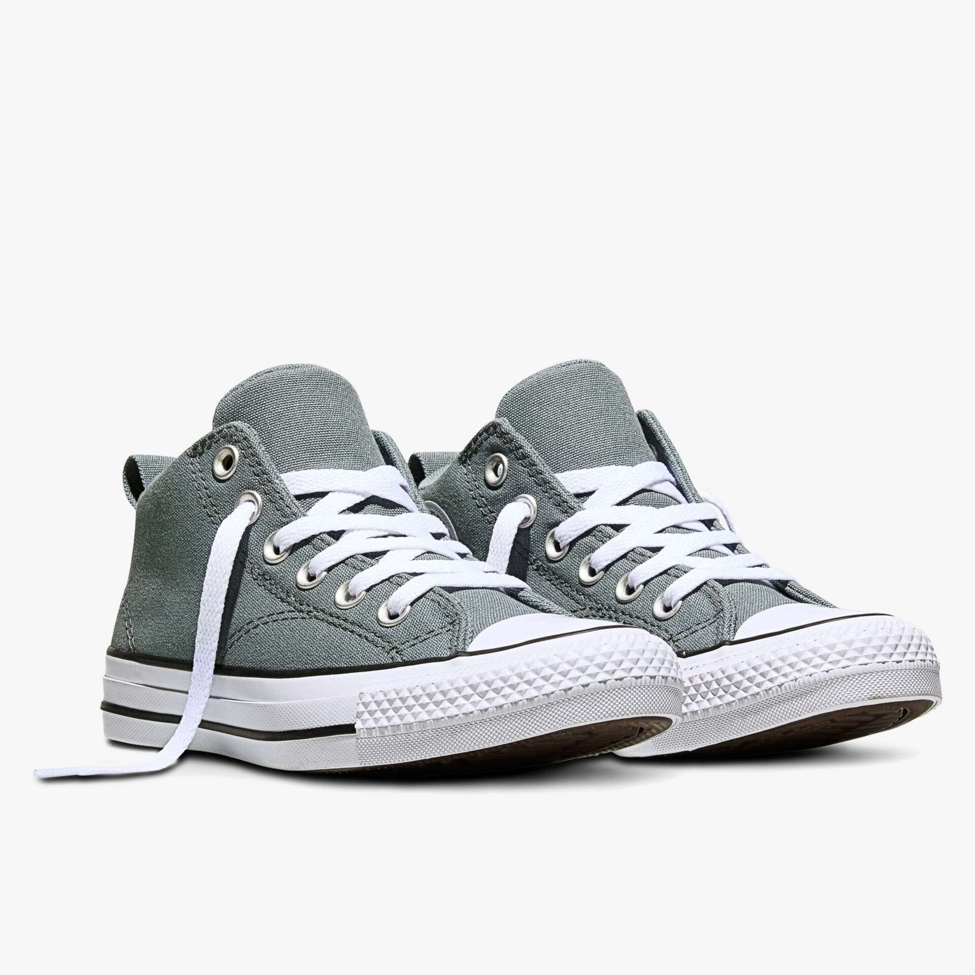 Zwei grüne Canvas Sneaker mit weißer Gummisohle und Schnürung in schräger Frontansicht auf weißem Hintergrund