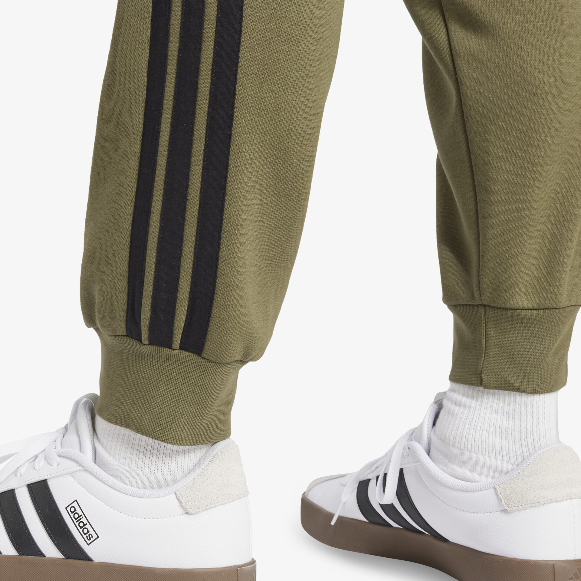 Seitliche Ansicht eines weißen Sportschuhs mit schwarzen Streifen und bequemer Passform an Socke und Hose