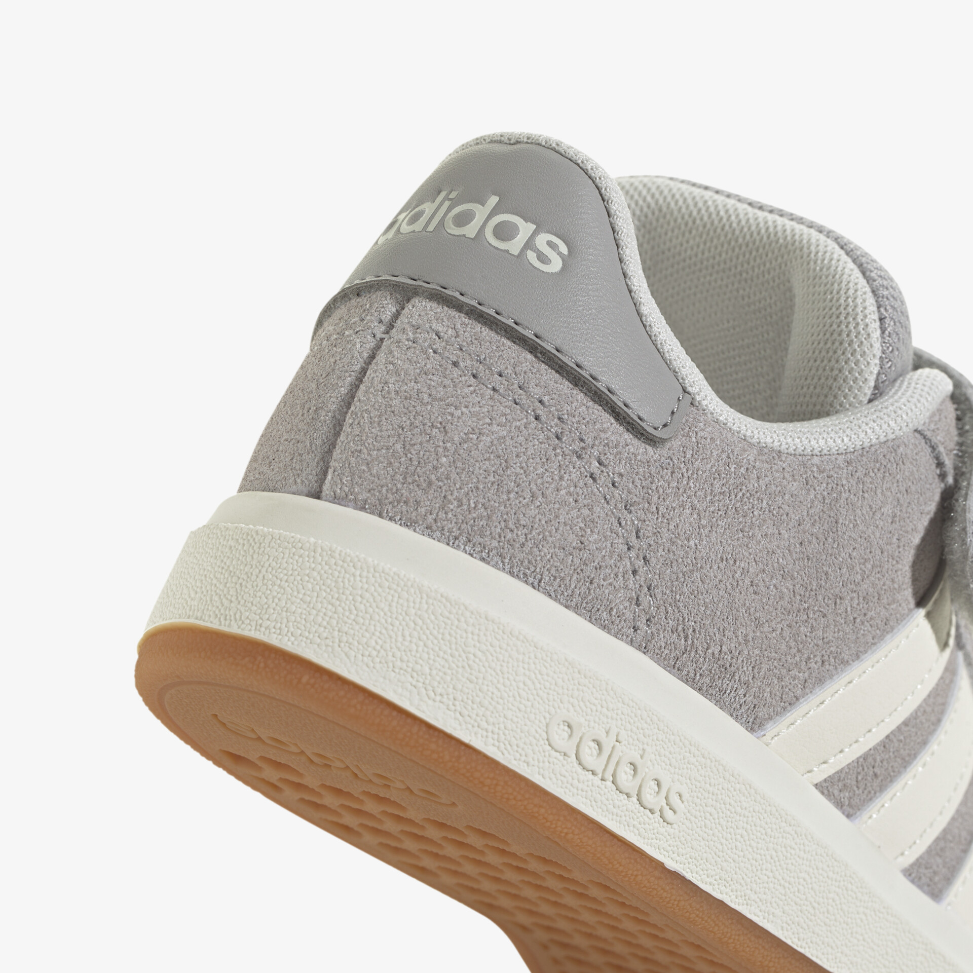 Detailansicht eines grauen Adidas Sneakers mit klar sichtbarem Logo und robuster weißer rutschfester Gummisohle
