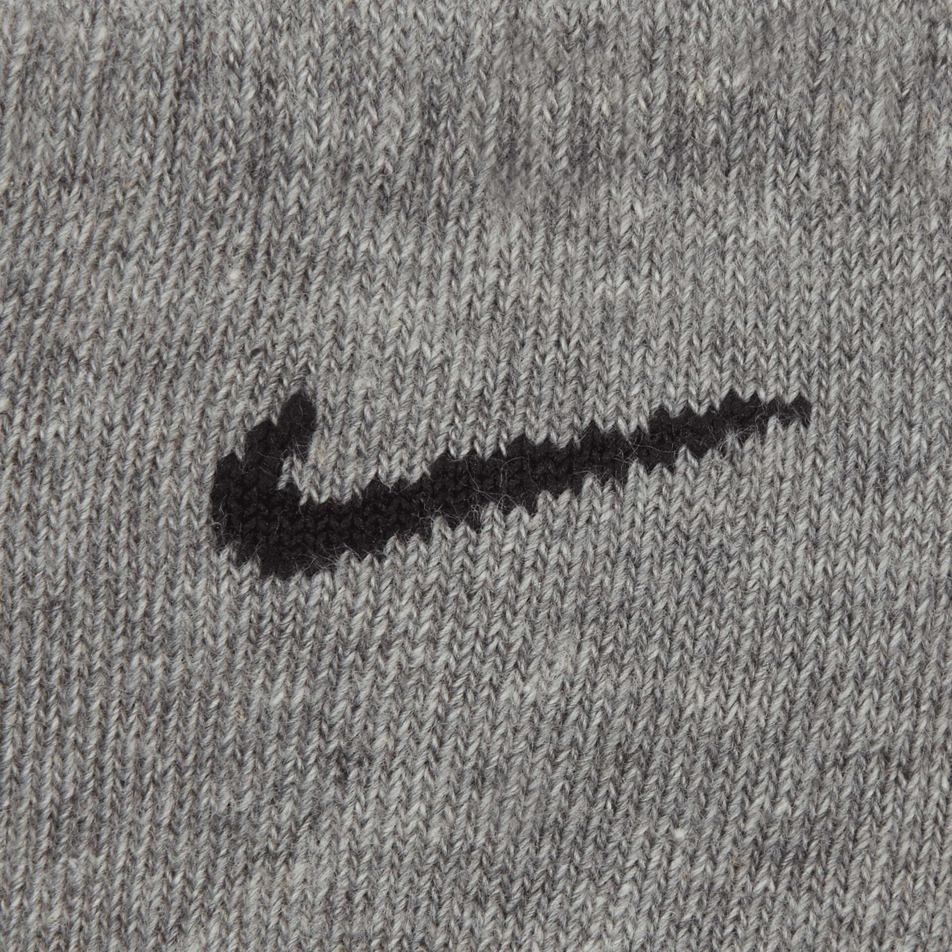 Detailaufnahme des schwarzen Nike Logos auf grauem Stoff mit klaren Linien und hochwertigem Material