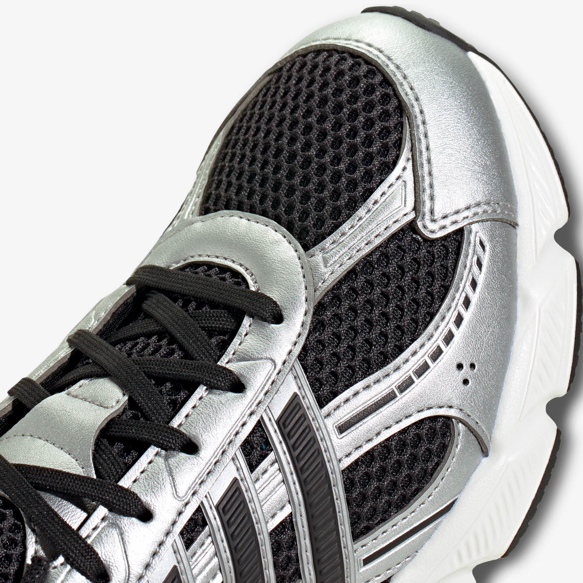 Detailaufnahme eines Sportschuhs mit atmungsaktivem Mesh und stabilisierenden Overlays aus silbernem Material