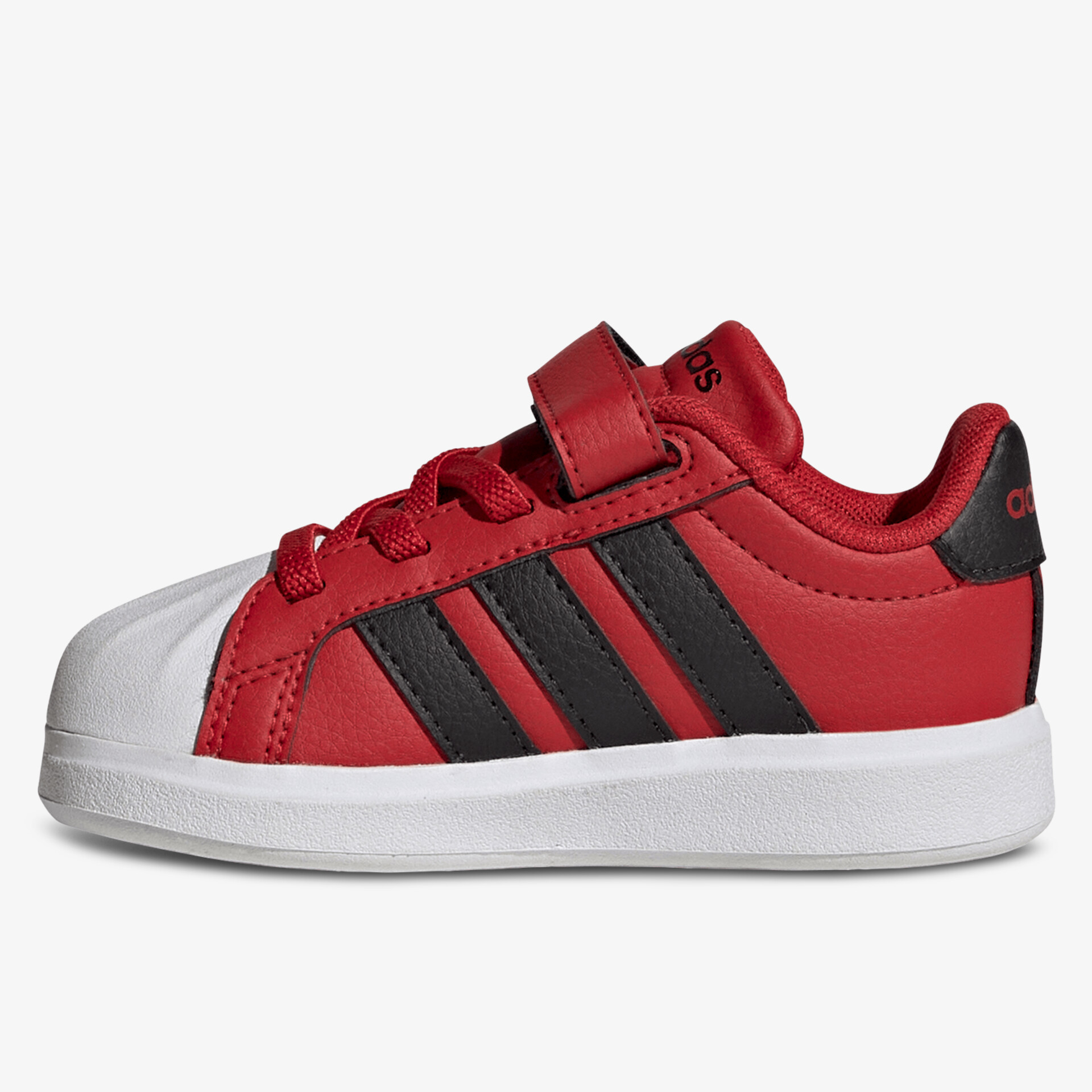 Seitliche Ansicht eines roten Sportschuhs mit schwarzen Streifen, rutschfeste weiße Sohle und Klettverschluss