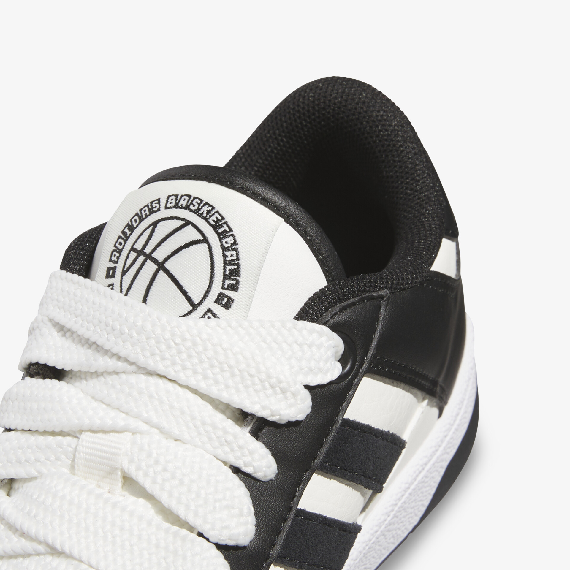 Nahaufnahme eines sportlichen Schuhs mit weißer Schnürung und markantem Logo auf der Zunge