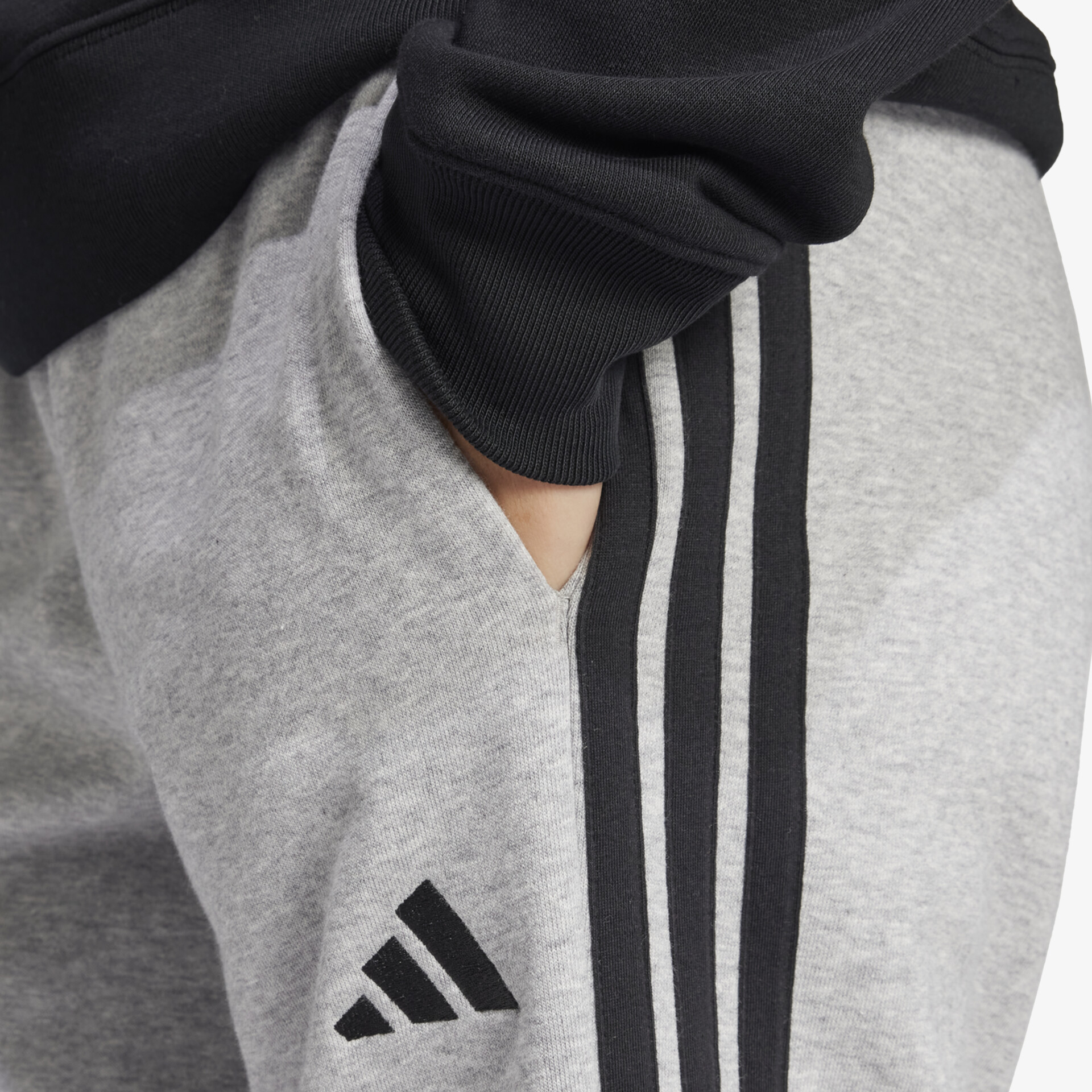 Detailaufnahme grauer Sporthose mit elastischem Bund, Seitentasche und markantem Logo für komfortable Bewegungsfreiheit