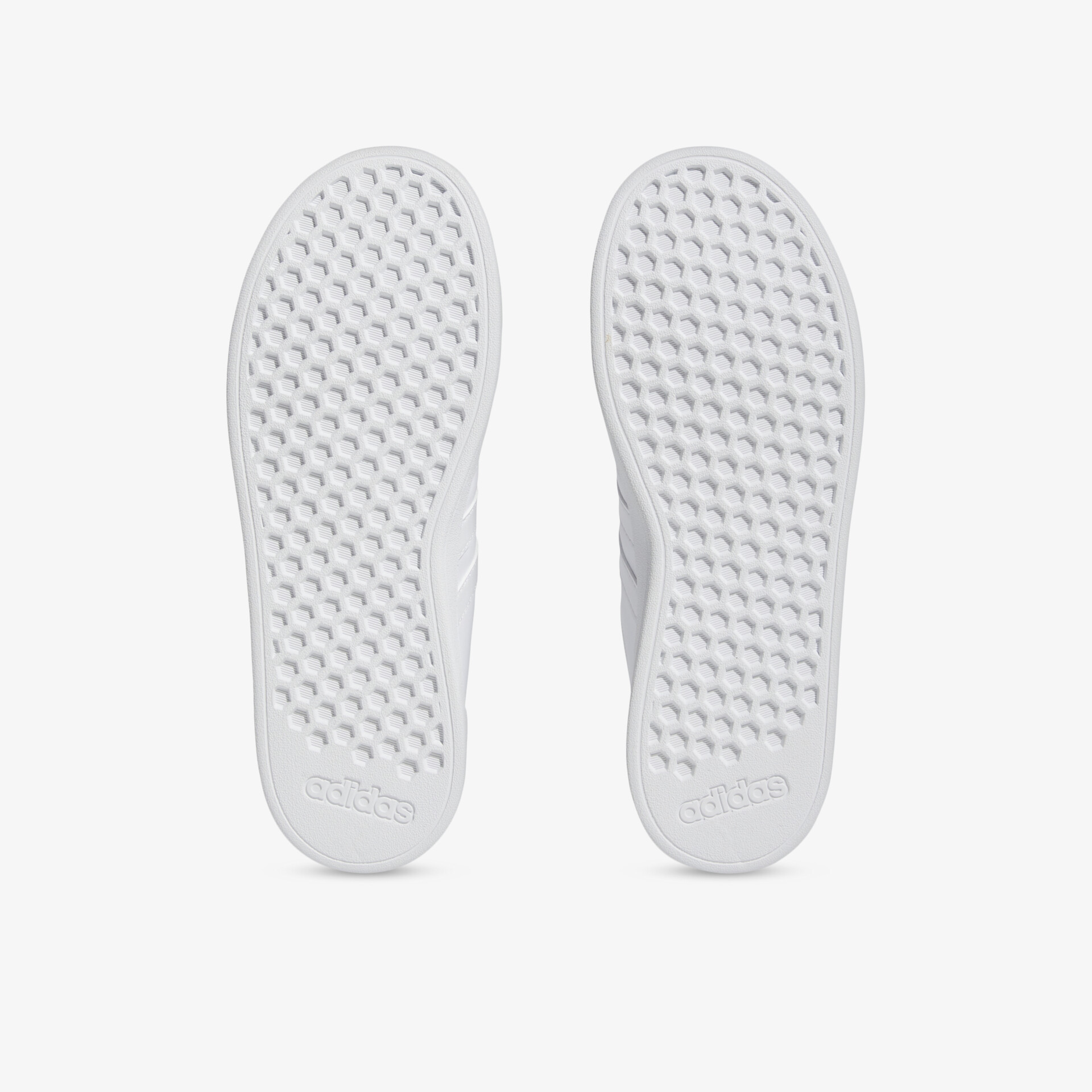 Bild zeigt die rutschfesten Sohlen eines weißen Schuhpaars mit flexiblem, langlebigem Profil