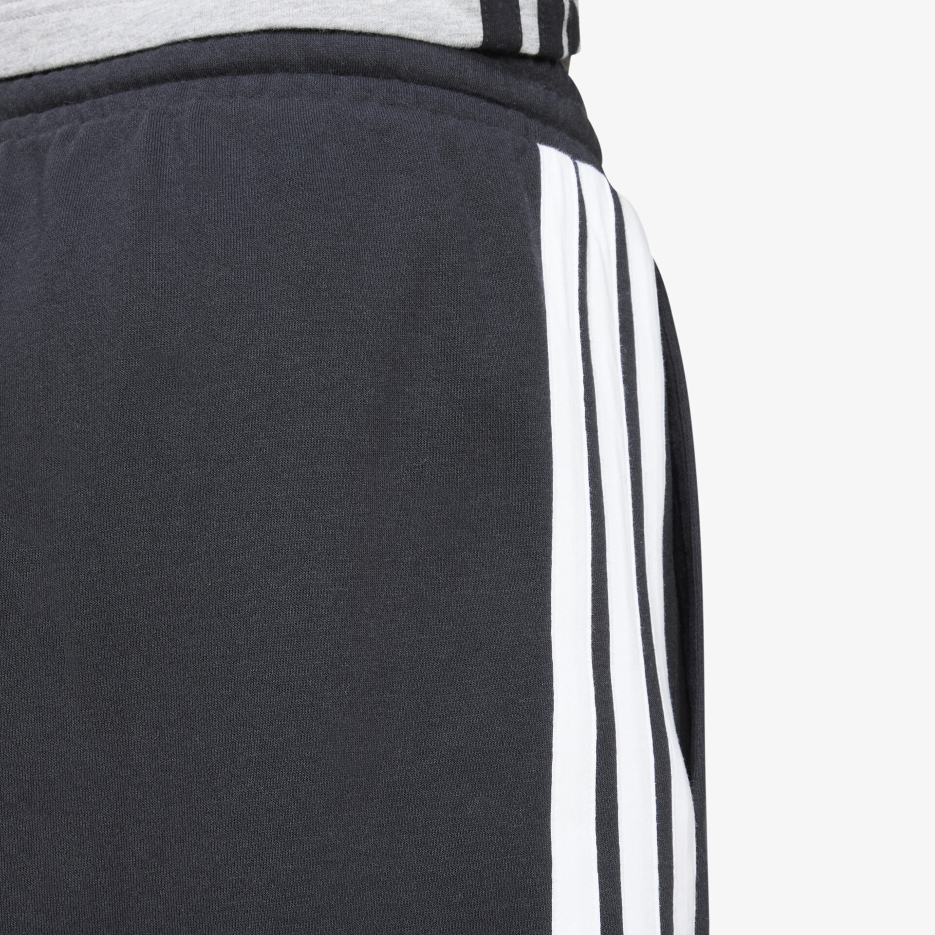 Schwarze Sporthose mit weißen Streifen, elastisches Material und präzise Nähte als Detailaufnahme