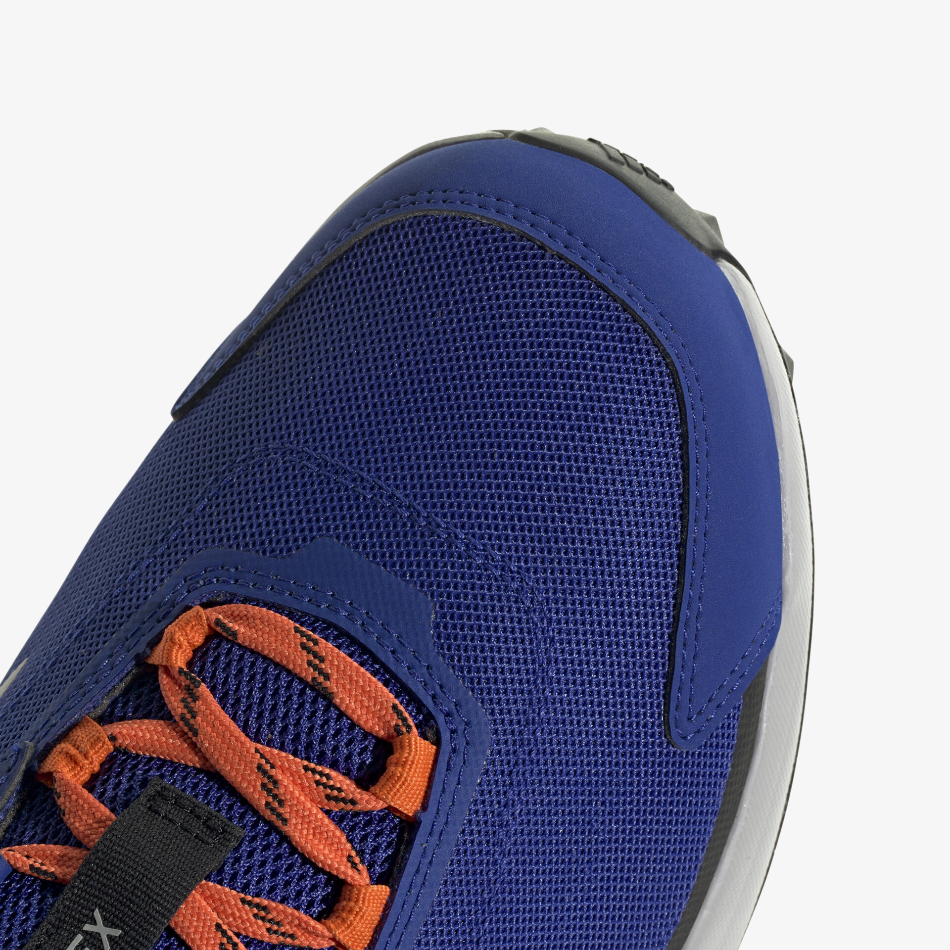Detailansicht eines blauen Sneakers mit orangefarbenen Schnürsenkeln, atmungsaktiv und robust