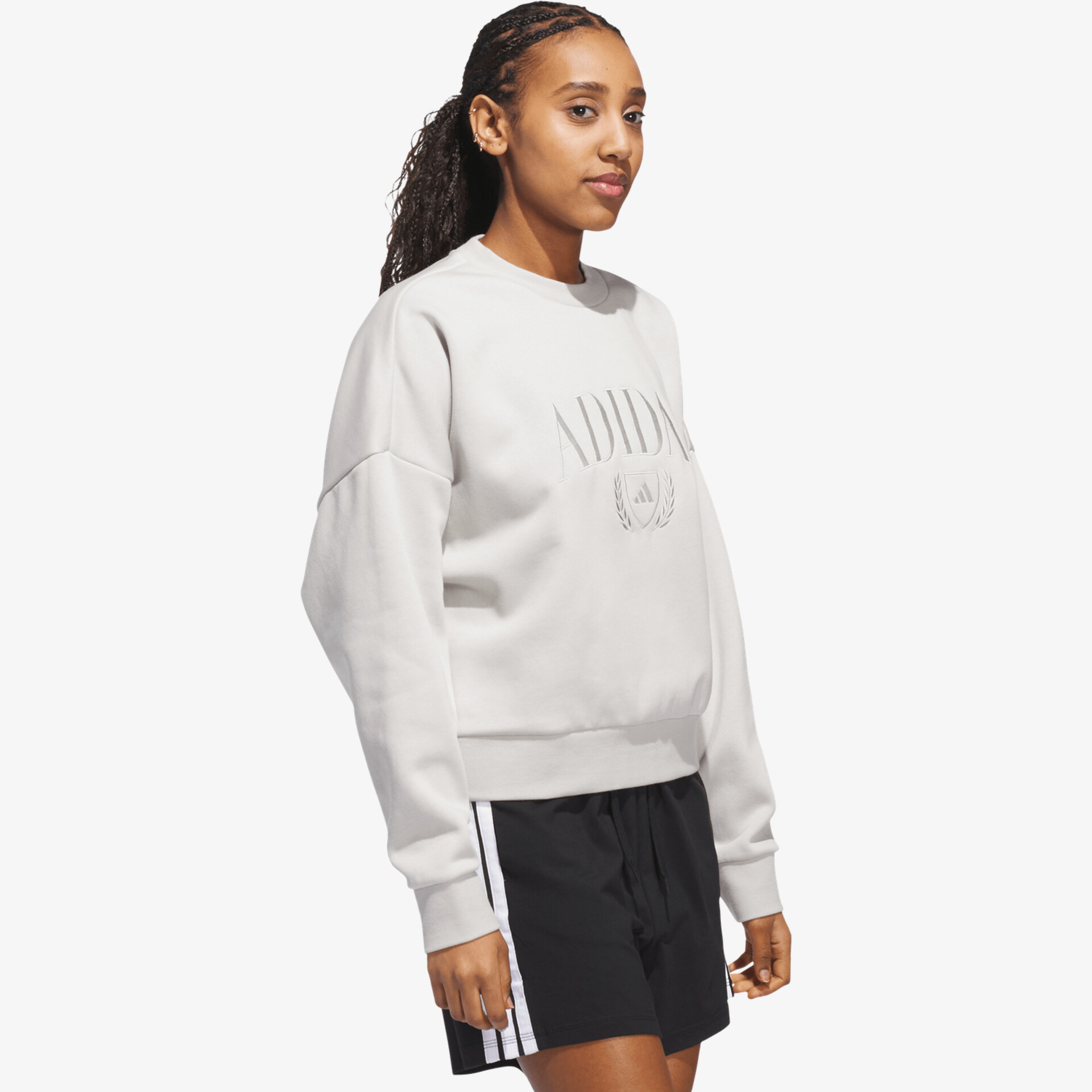 Modell trägt weißen Pullover mit Rundhalsausschnitt und lockerer Passform, kombiniert mit schwarzer Hose