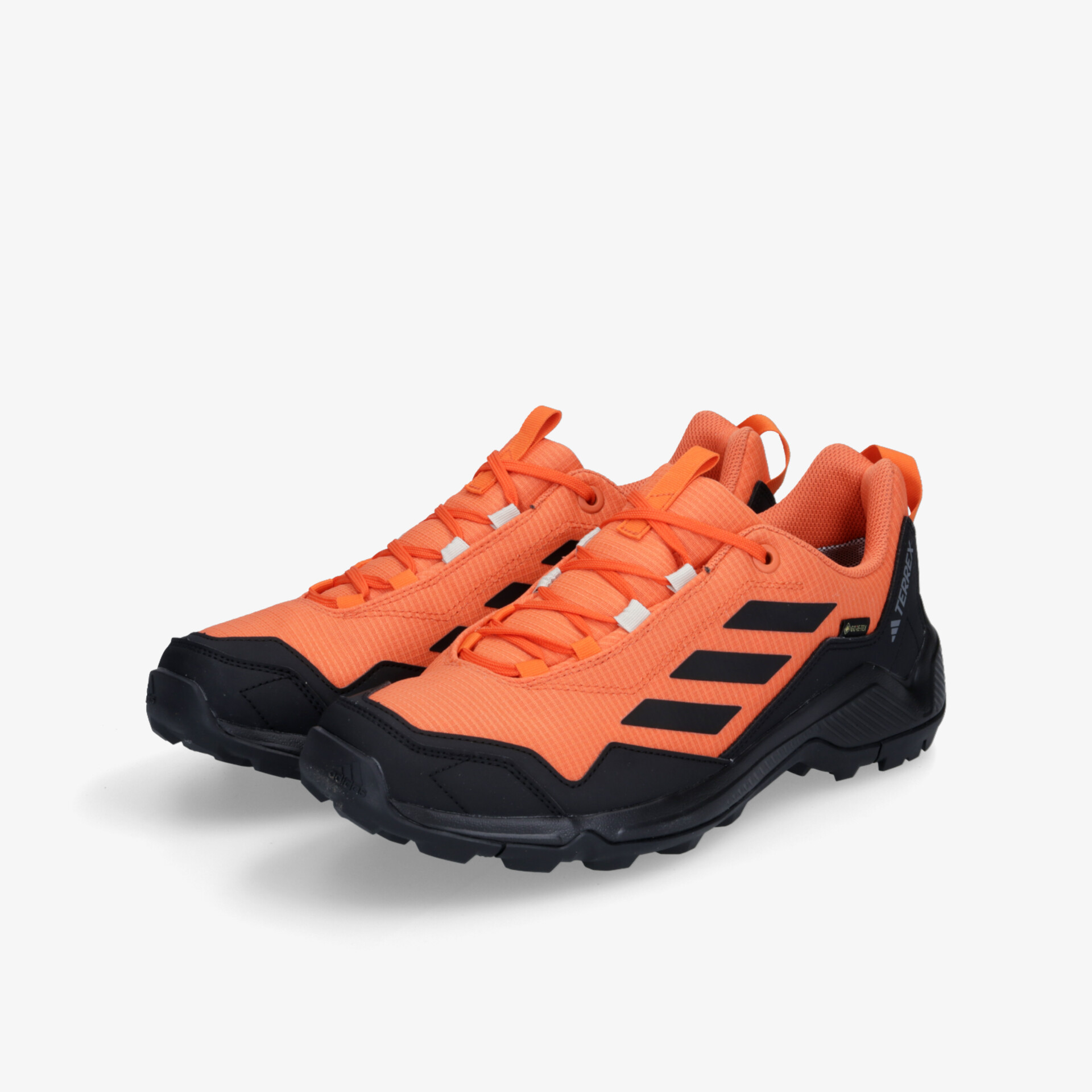 Robuste und sportliche orange-schwarze Sportschuhe mit griffiger Sohle und komfortablem Sitz im Paar an schräger Vorderansicht