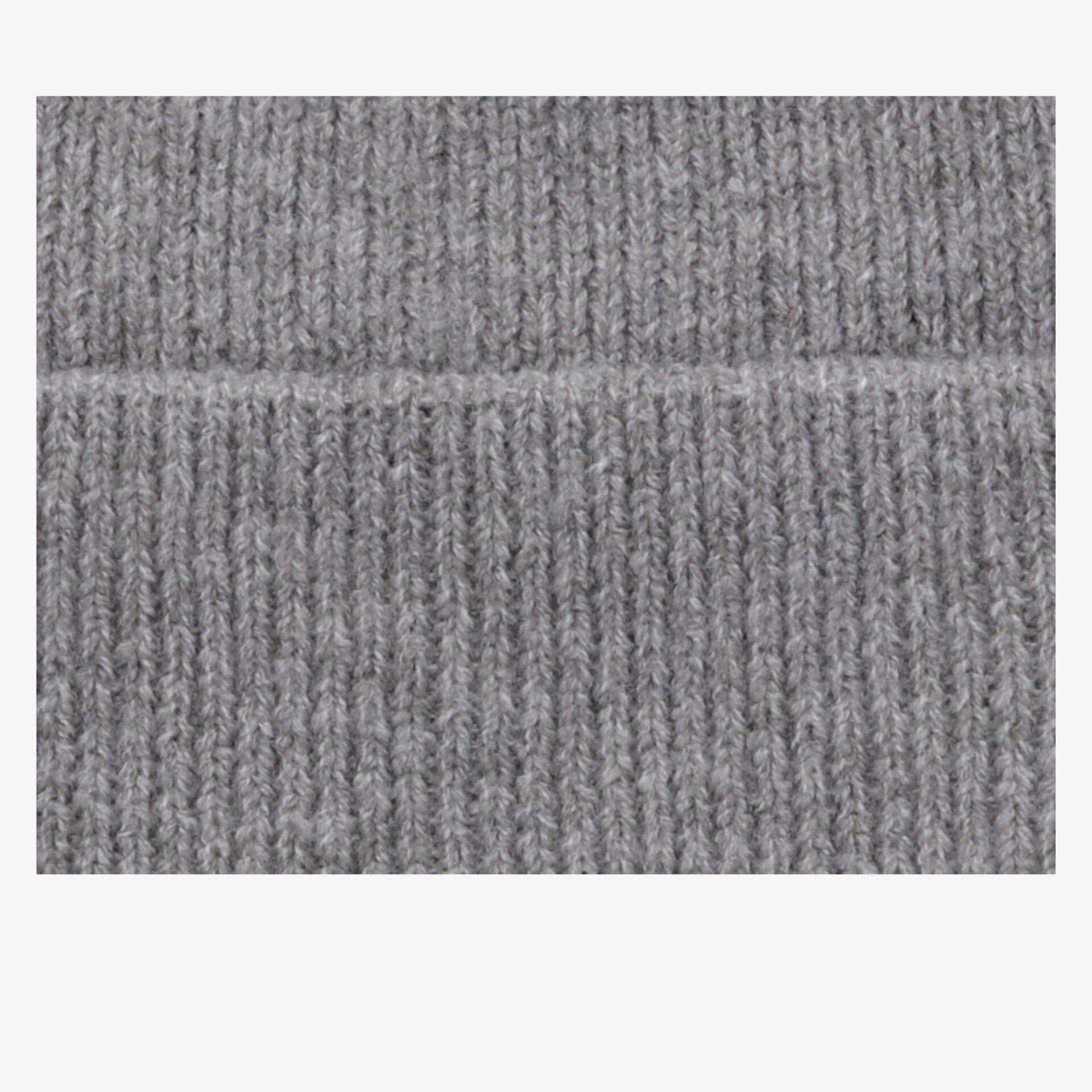 Detailaufnahme von grauem Stoff mit sichtbarer Naht und feiner Struktur, weiches und hochwertiges Material