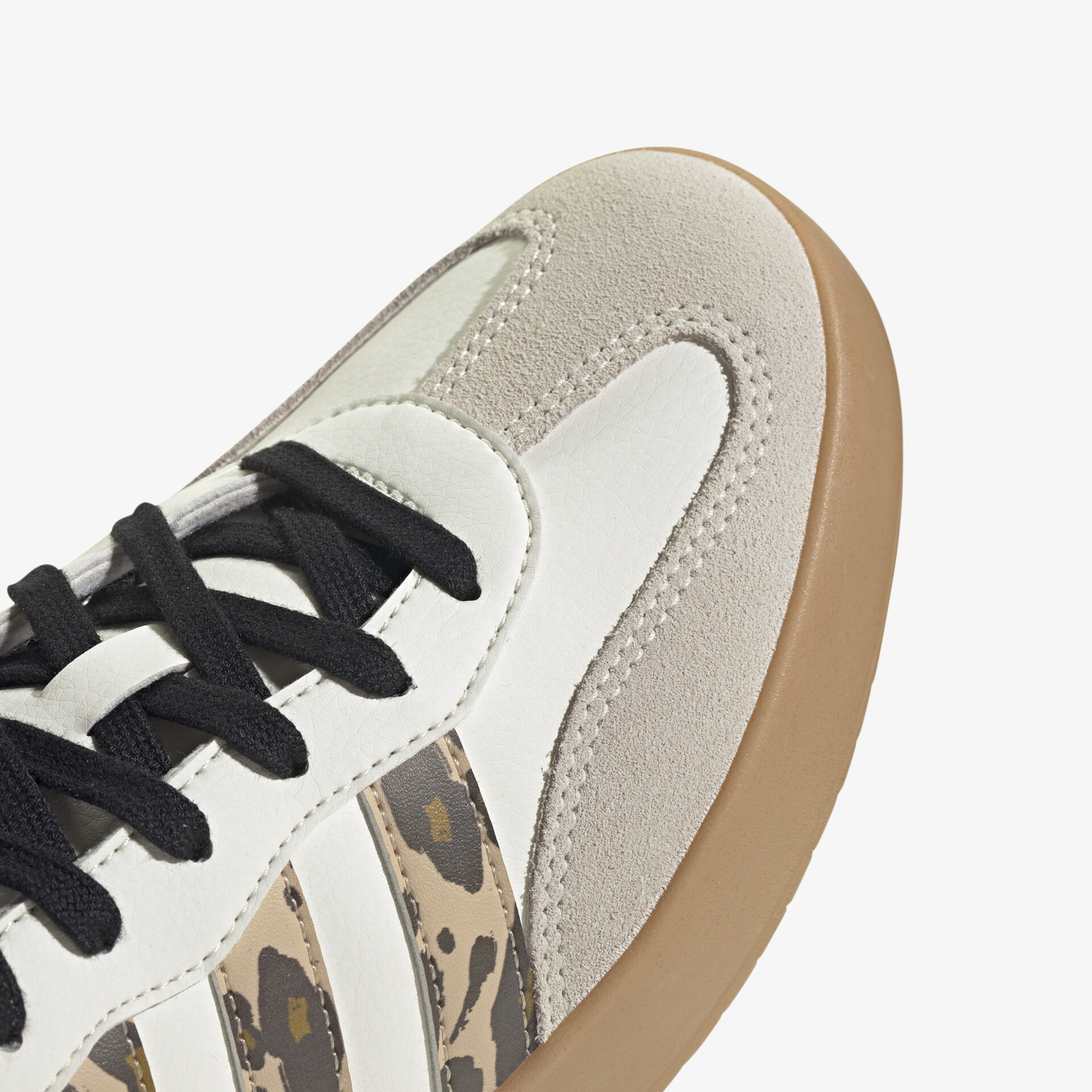 Detailaufnahme eines beigen und weißen Sneakers mit schwarzen Schnürsenkeln und feiner Textur