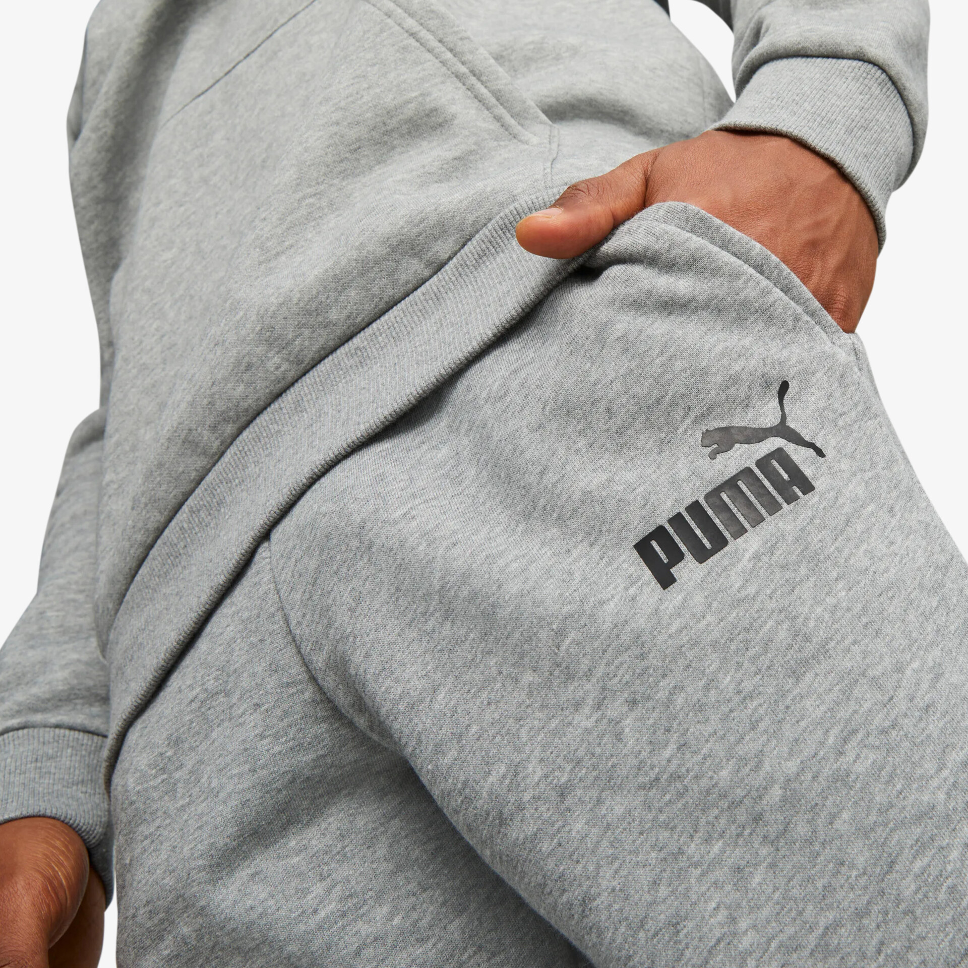 Detailaufnahme einer grauen Freizeithose mit sichtbarem schwarzen Puma Logo und komfortablem elastischem Bund