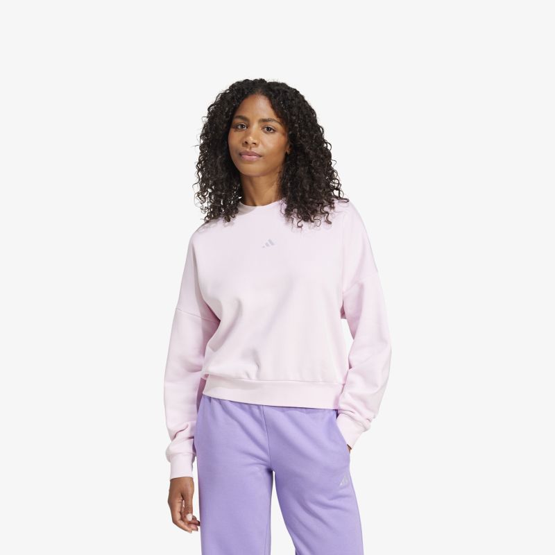 Weicher rosa Pullover mit entspanntem Schnitt kombiniert mit lila Hose auf hellem Hintergrund