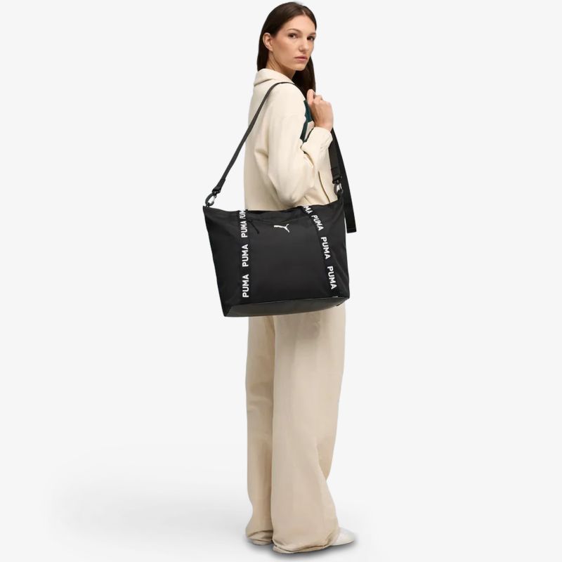 Elegante schwarze Tasche mit weißen Logodetails, großer Stauraum und praktischem Tragegriff am Körper getragen