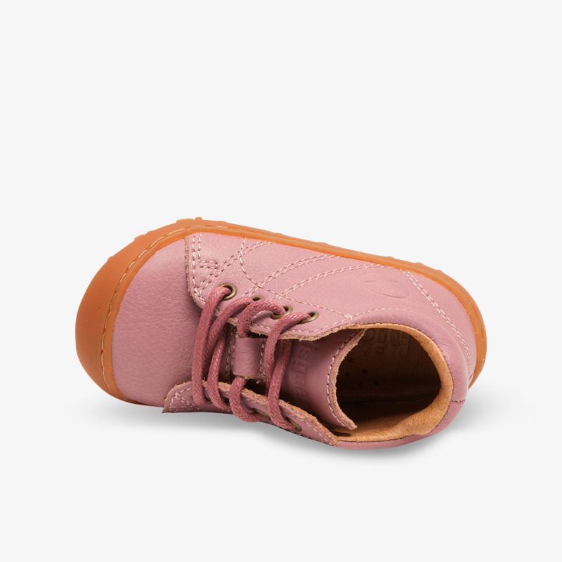 Bequemer rosa Schuh liegend auf der Oberseite mit flexibler Schnürung und robuster, rutschfester Sohle