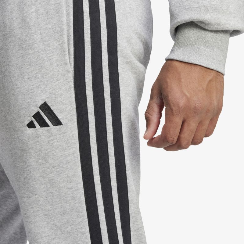 Detailaufnahme einer grauen Jogginghose mit drei schwarzen Streifen und Markenlogo, weicher bequemer Stoff