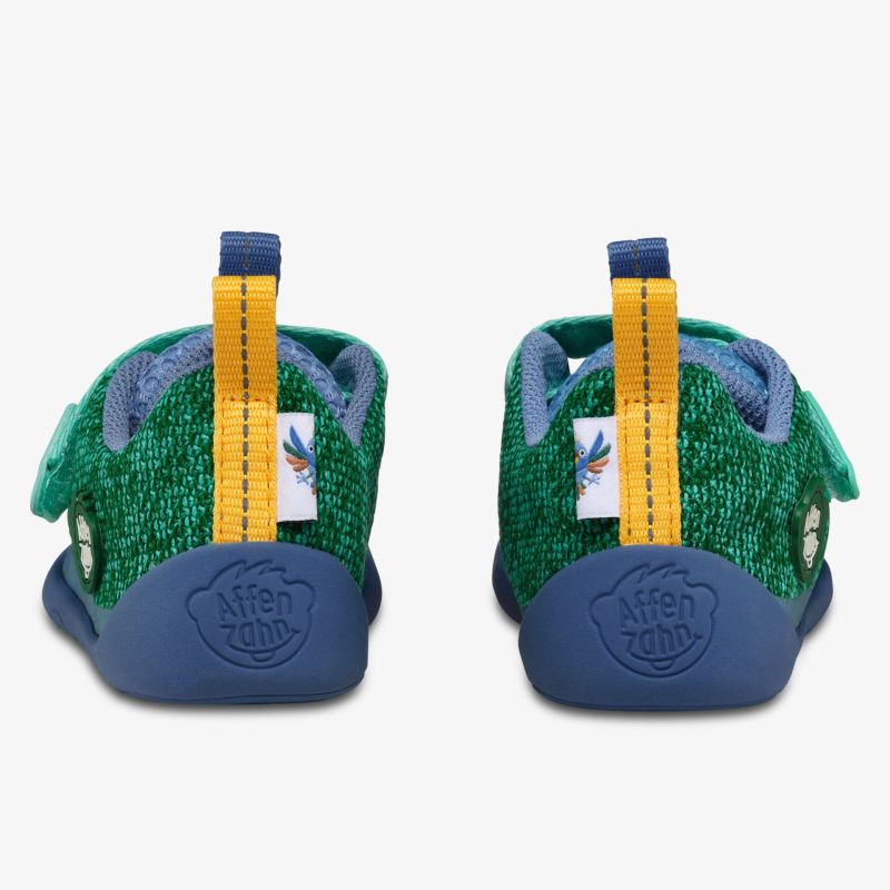 Rückansicht von grünen Hausschuhen mit rutschfester Sohle und elastischem Verschluss für sicheren Halt