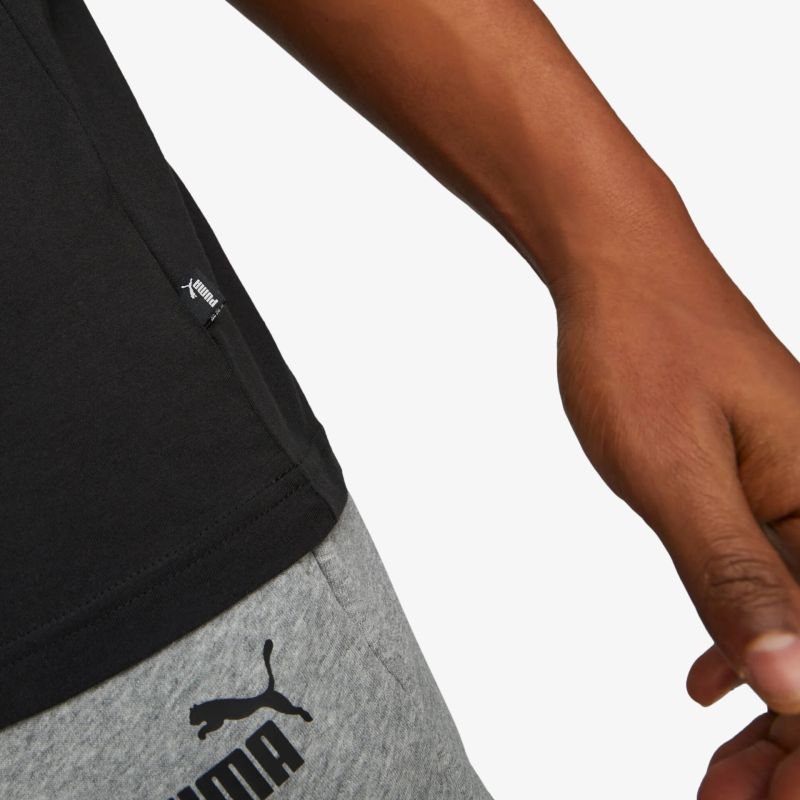 Detailaufnahme eines sportlichen, elastischen und bequemen Puma-Hosenstoffs mit sichtbarem Logo und Hand