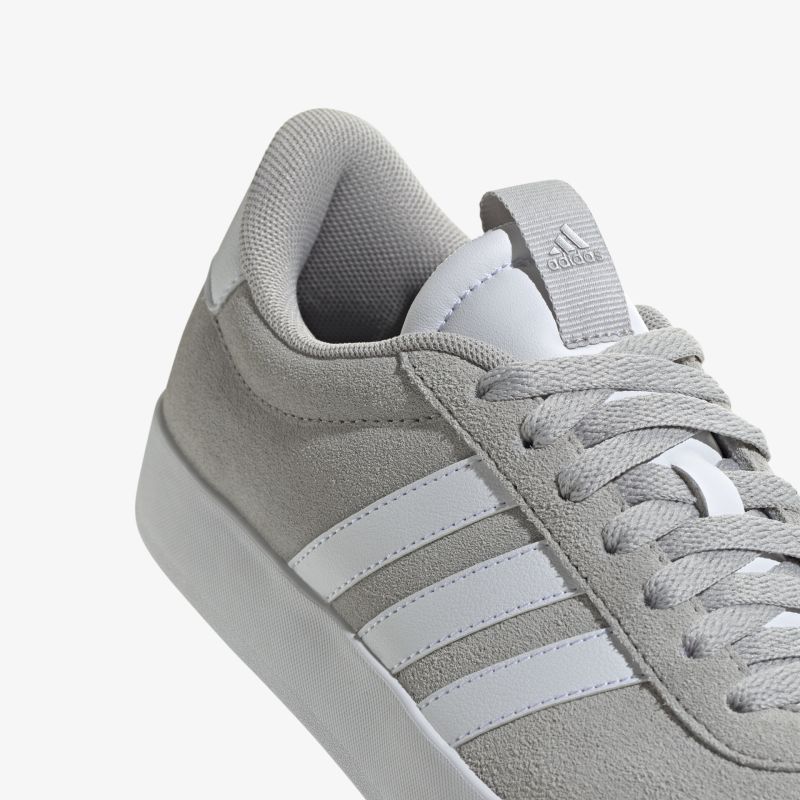 Detailaufnahme eines grauen Sneakers mit weißen Streifen und Schnürsenkeln, weiches komfortables Material