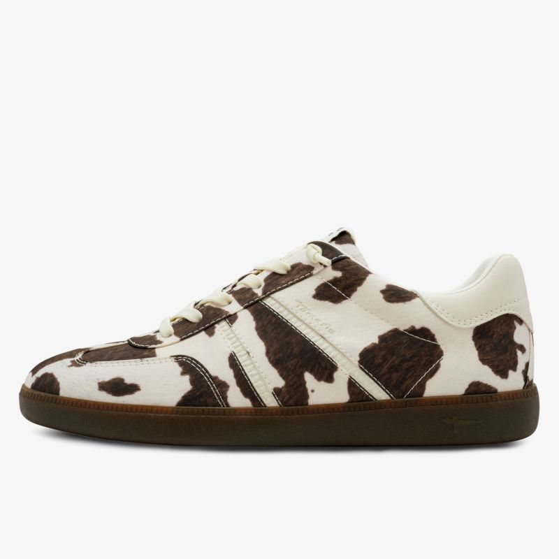 Seitliche Ansicht eines modischen Sneakers mit Kuhfellmuster und brauner Sohle, hochwertige Verarbeitung sichtbar