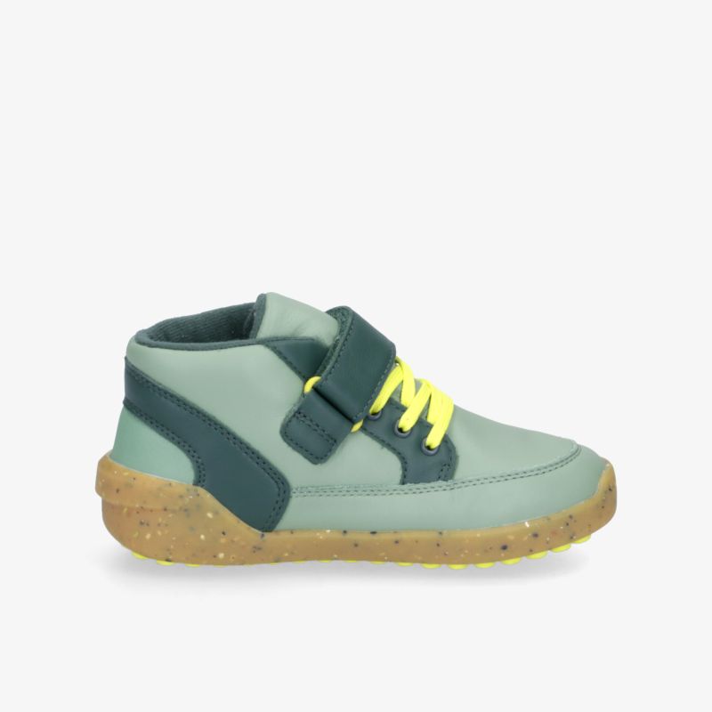 Moderner grüner Schuh mit gelben Schnürsenkeln und Klettverschluss, robuste Sohle für bequemen Tragekomfort.