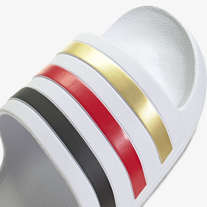 Weißer Schuh mit breiten goldfarbenen, roten und schwarzen Riemen, modernes Design, komfortabel und strapazierfähig
