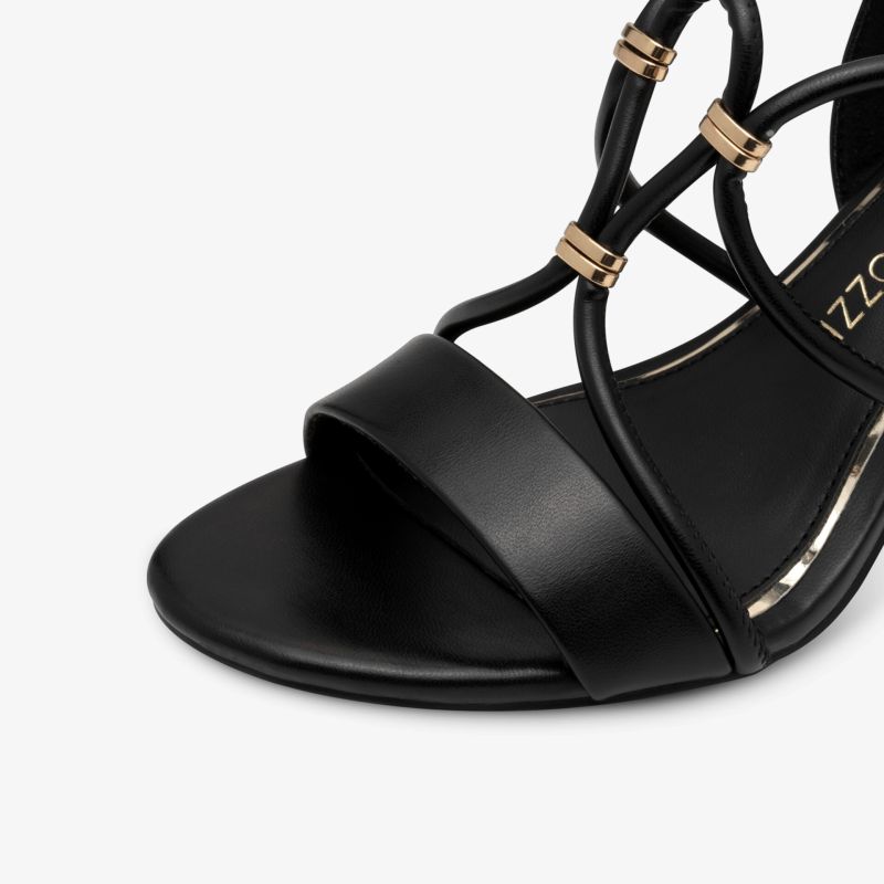 Detailaufnahme einer schwarzen Sandalette mit eleganten Riemen und goldenen Schmuckelementen in hochwertiger Verarbeitung