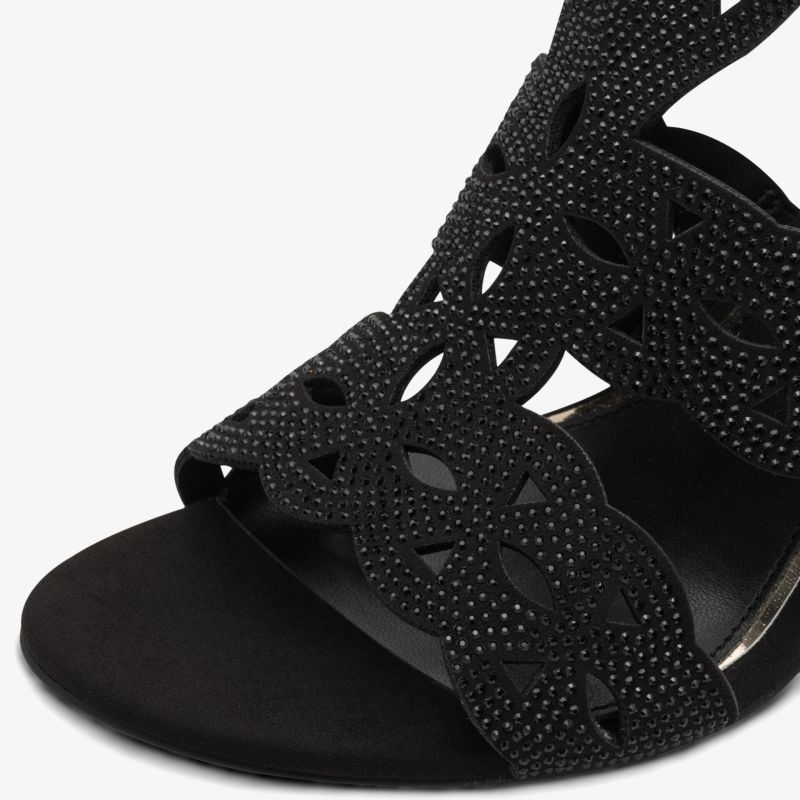 Detailaufnahme schwarzer Sandale mit feinem Strassbesatz und elegantem Ausstanzungsmuster auf geschwungenen Riemen