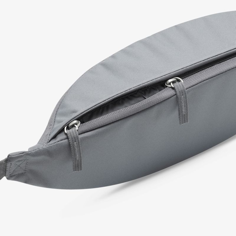 Graue Bauchtasche mit geöffnetem Reißverschluss, kompakter und funktionaler Begleiter für den Alltag