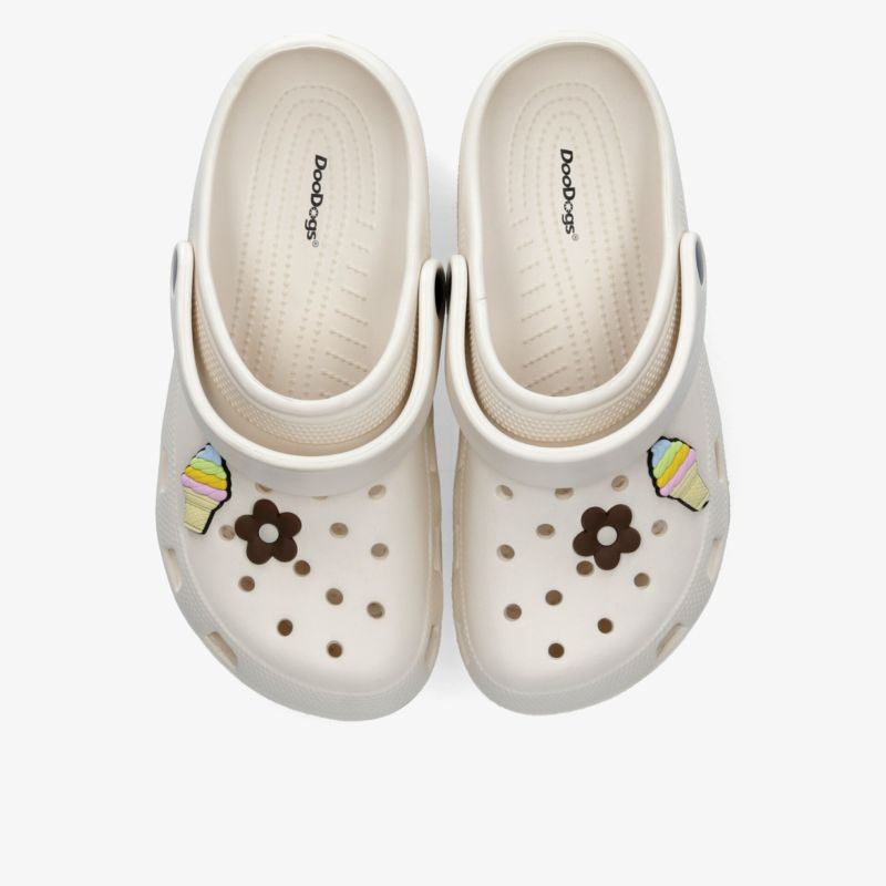 Komfortable weiße Clogs mit dekorativen Pins und perforiertem Design, ideal für Freizeit und Alltag.