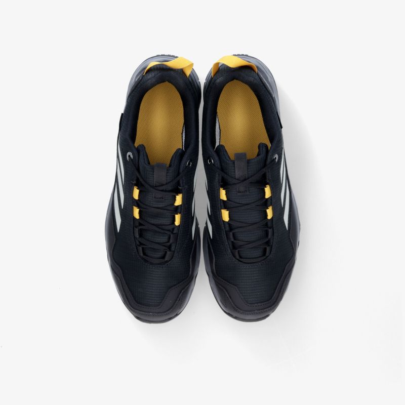 Schwarze Sportschuhe mit gelben Akzenten und markanten Streifen, optimal für sportliche Aktivitäten.