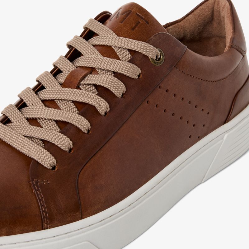 Moderner brauner Ledersneaker mit weißer Sohle und beigen Schnürsenkeln, sportlich und bequem