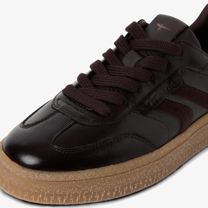 Detailaufnahme eines dunkelbraunen Ledersneakers mit robusten Schnürsenkeln und gummierter Sohle