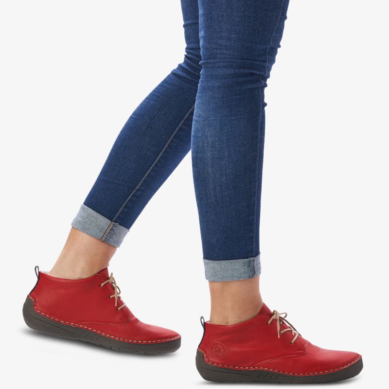 Rote Schnürschuhe mit flexibler Sohle und bequemer Passform, getragen an den Füßen in lässiger Jeans