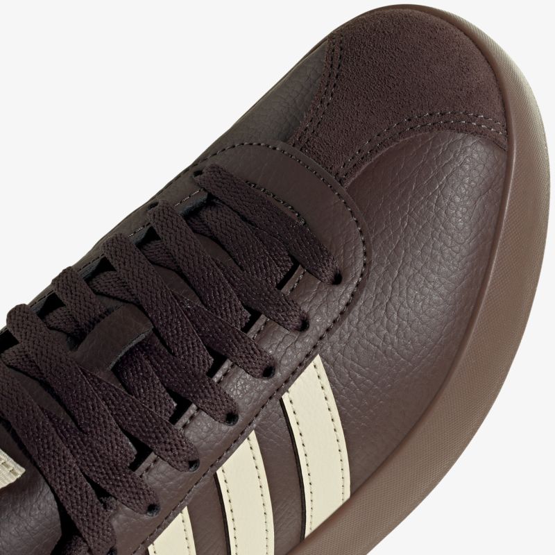Sportlicher brauner Schuh mit weißen Streifen und Schnürsenkeln, robustes Material und modernes Design