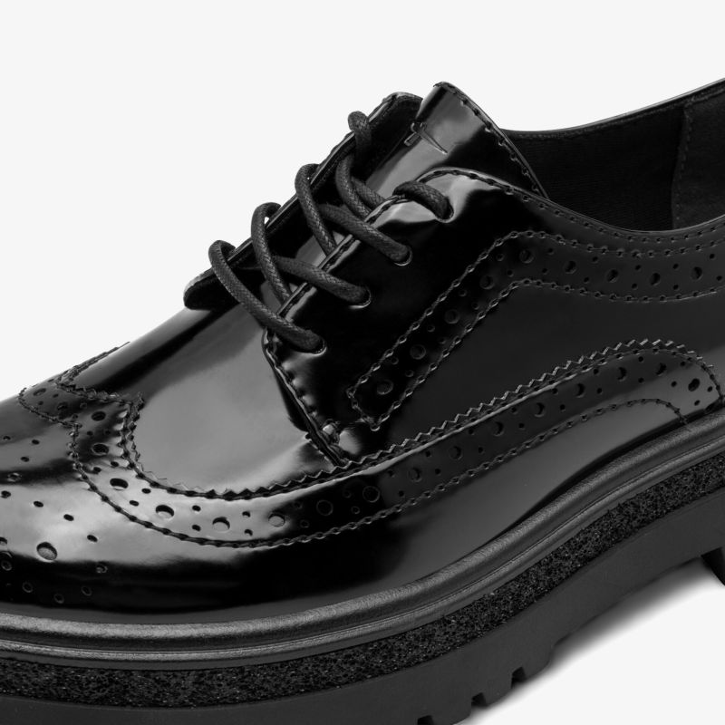 Schwarzer lackierter Schnürschuh mit Brogue-Details und glänzender Oberfläche in Nahaufnahme