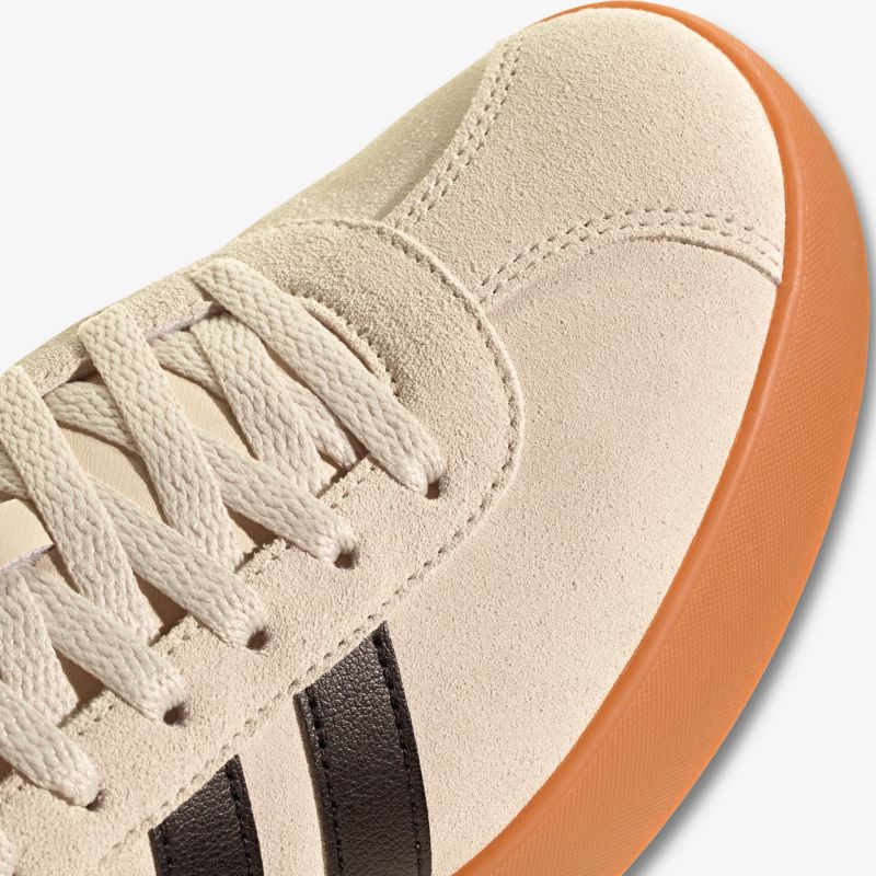 Detailansicht eines beigen Sneakers mit gummierter brauner Sohle und klassischer Schnürung